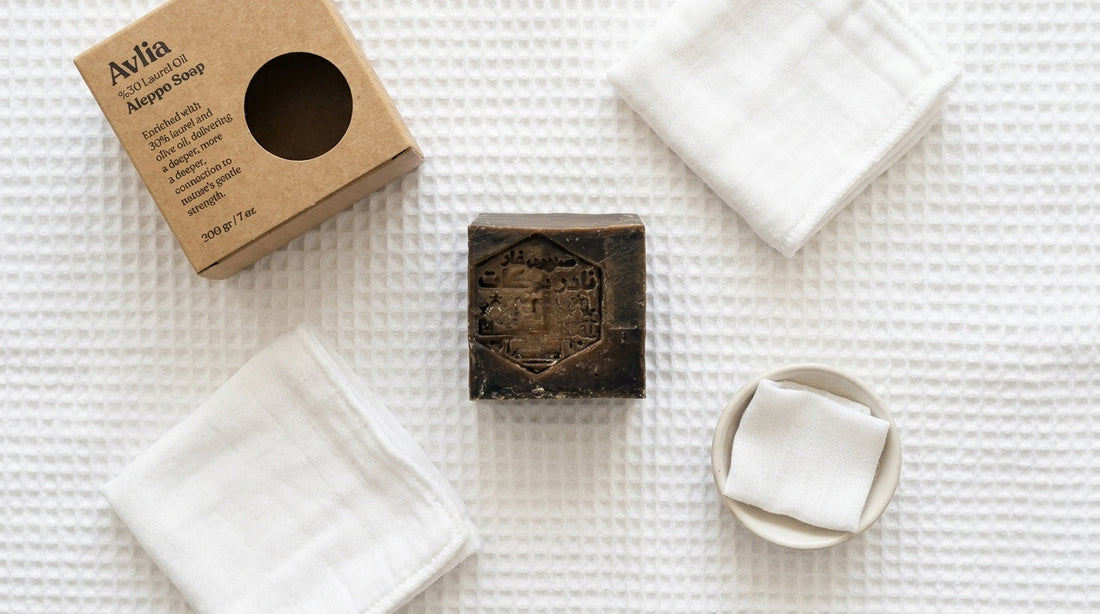 Avlia 30% Laurel Oil Aleppo Soap bar and kraft box overhead on white cotton terry cloth, gentle minimal baby-safe soap