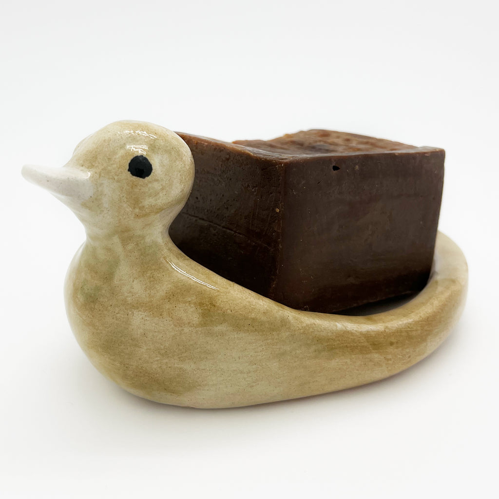 A bar of Aleppo soap in the Avlia ceramic duck soap dish in pale cream glaze, giving a clear sense of how much the shallow bowl holds