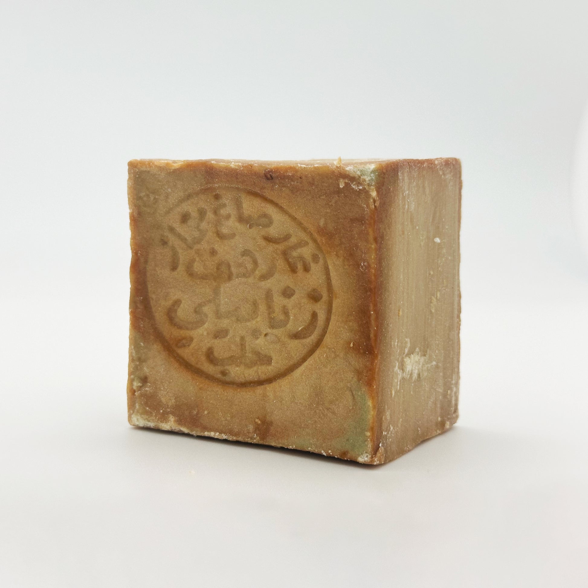 A perspective shot of the Avlia Aleppo soap bar, showing the thickness of the block and the matte texture of the 100% olive oil soap alongside the front stamp