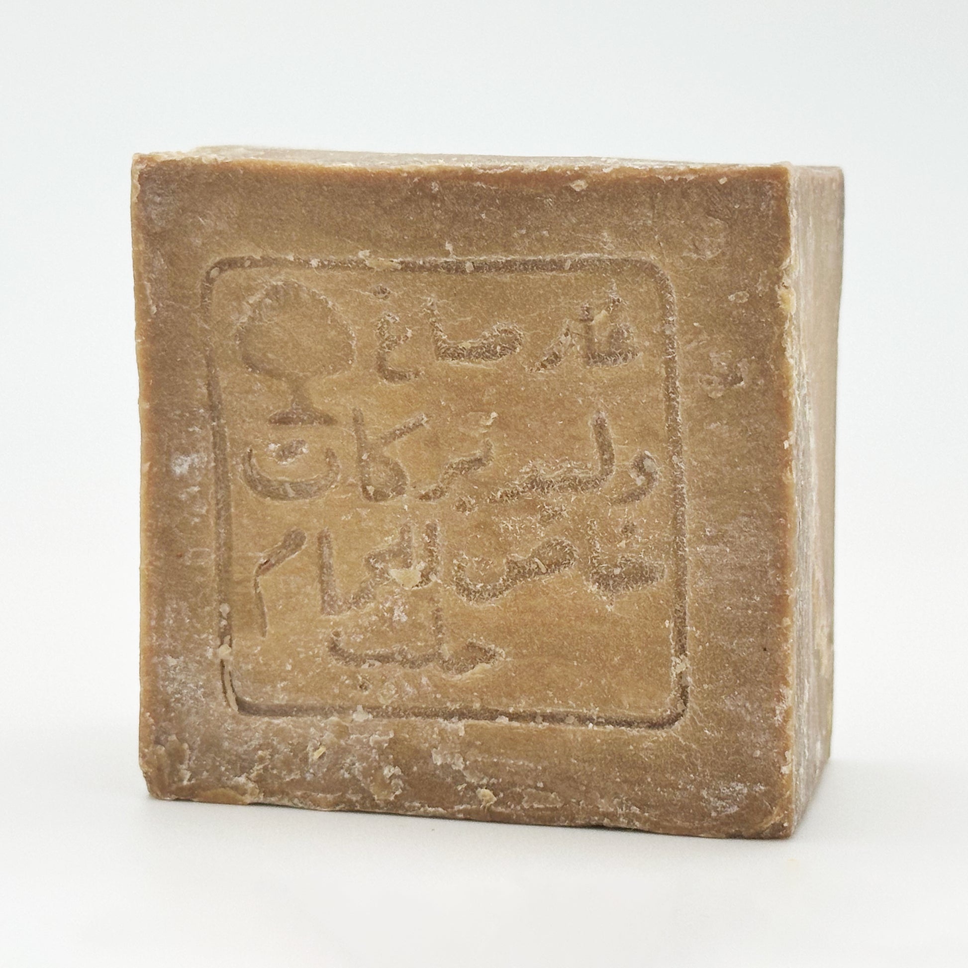 A detailed shot of the stamped soap bar at a slight angle, emphasizing the rustic, handmade edges and the fine, powdery curing bloom on the surface