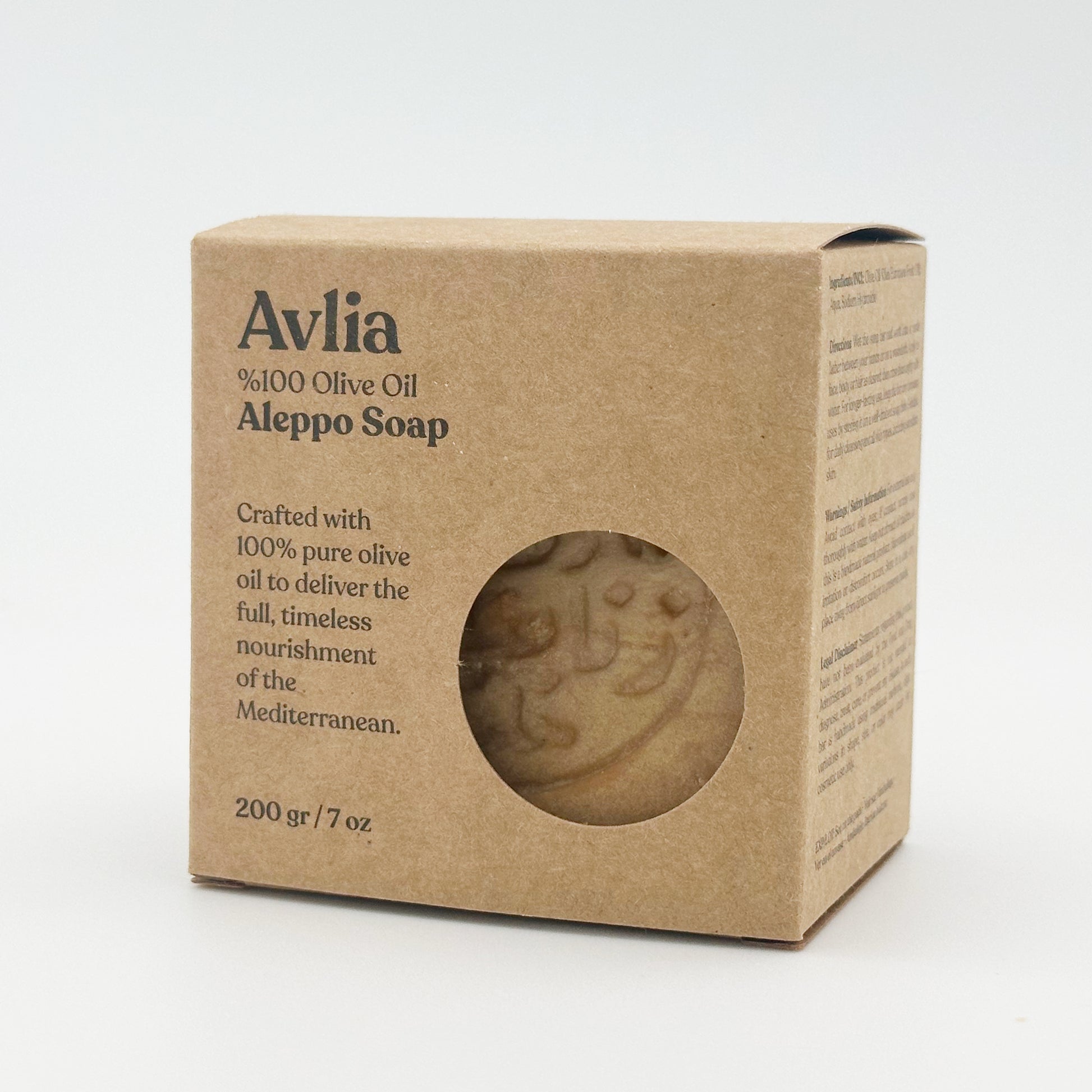 An angled view of the Avlia soap box, showing the front branding and the side panel with ingredients and directions, with the textured soap visible through the circular front window