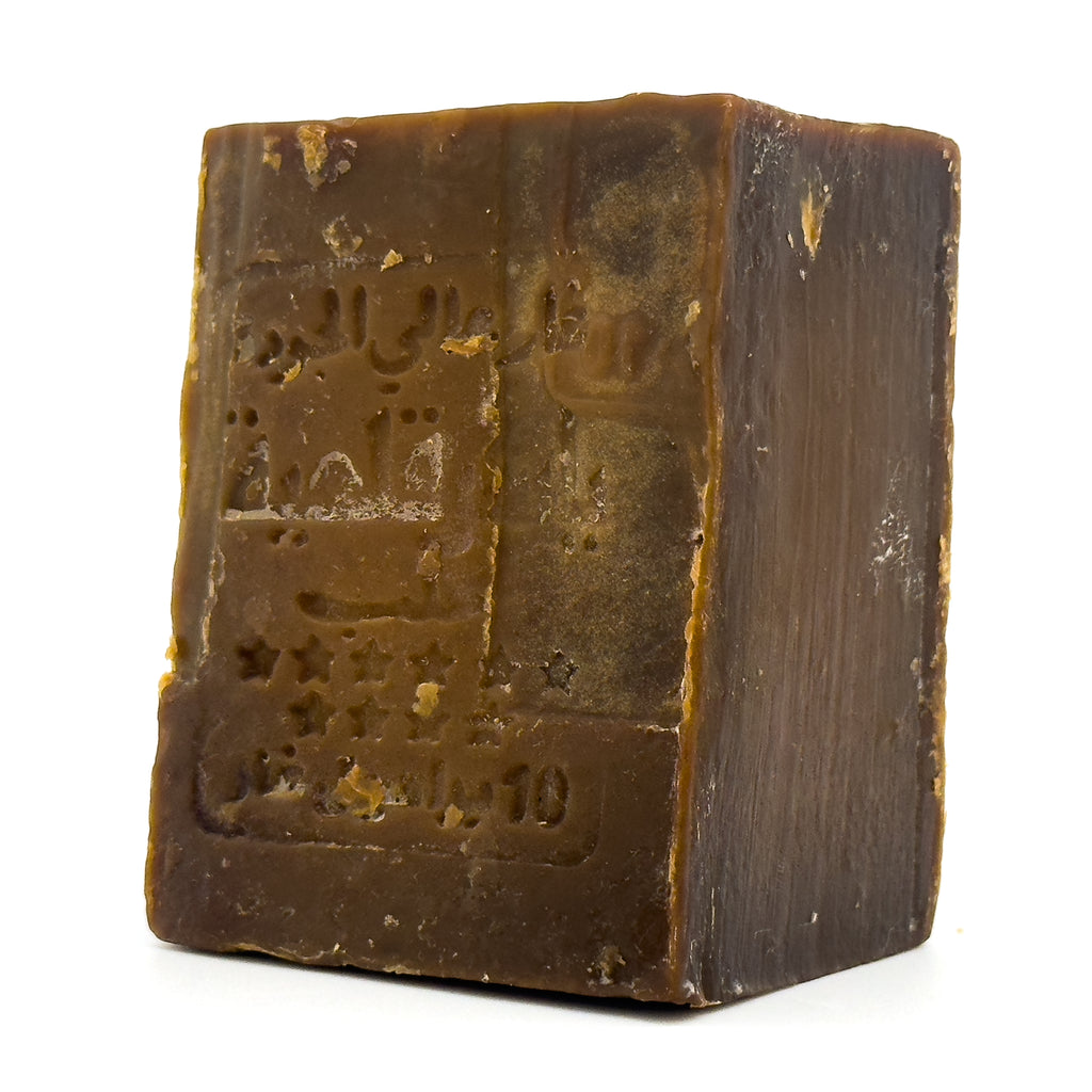 Angled close-up of an unwrapped Avlia Aleppo soap bar, showing the dark brown color and stamped Arabic calligraphy Portrait