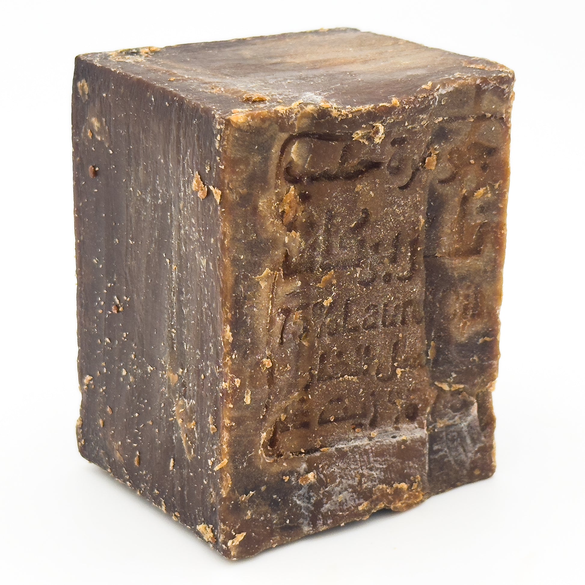 Angled close-up of unwrapped Avlia Aleppo soap block showing raw texture and stamped surface