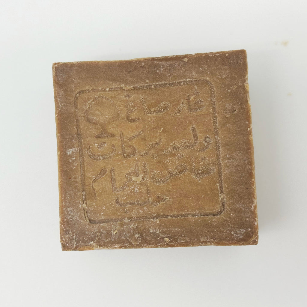 A top-down view of the soap bar’s square face, focusing on the depth and texture of the traditional manufacturer's stamp