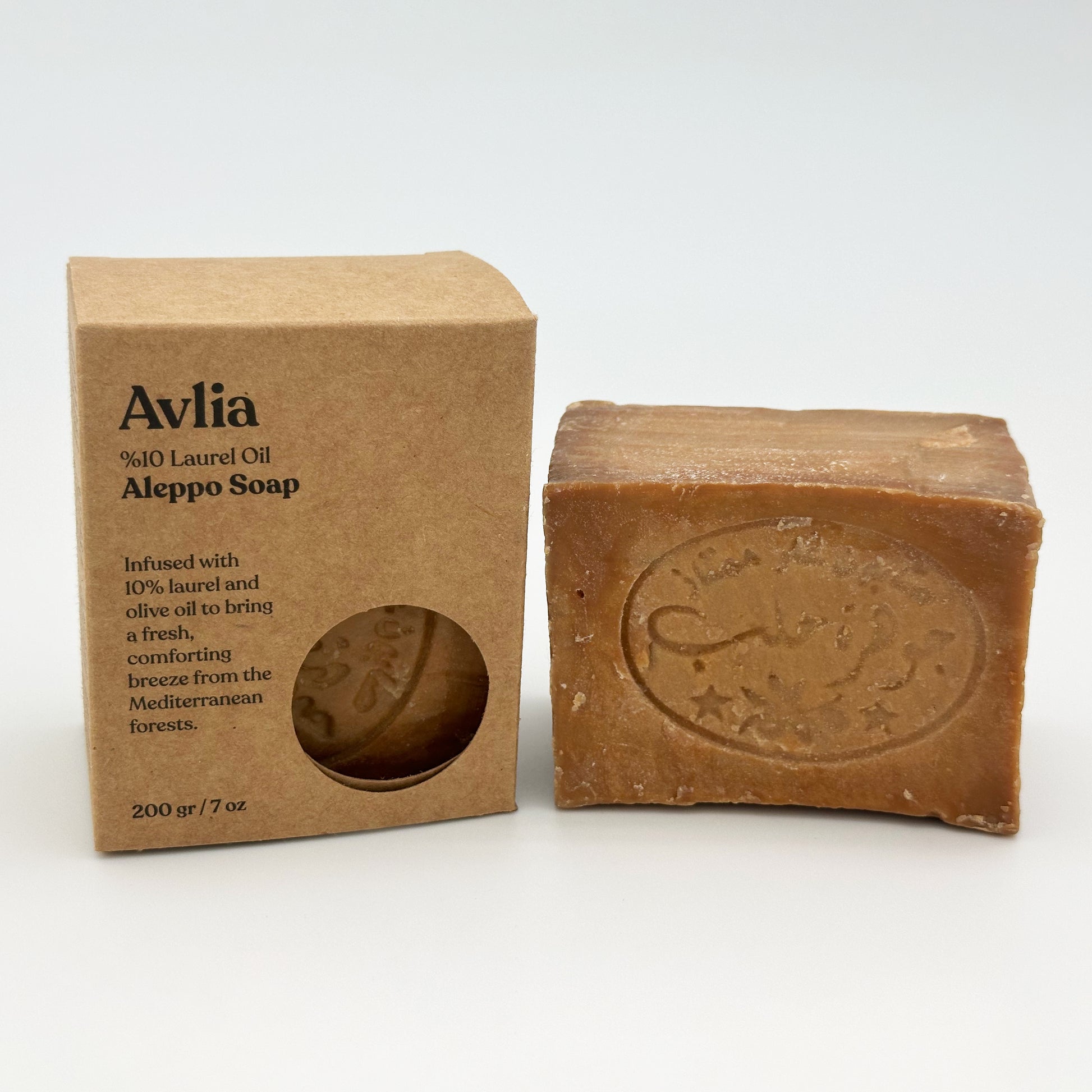 Avlia 10% Laurel Oil Aleppo Soap packaging box sitting next to the unwrapped bar of traditional Aleppo soap