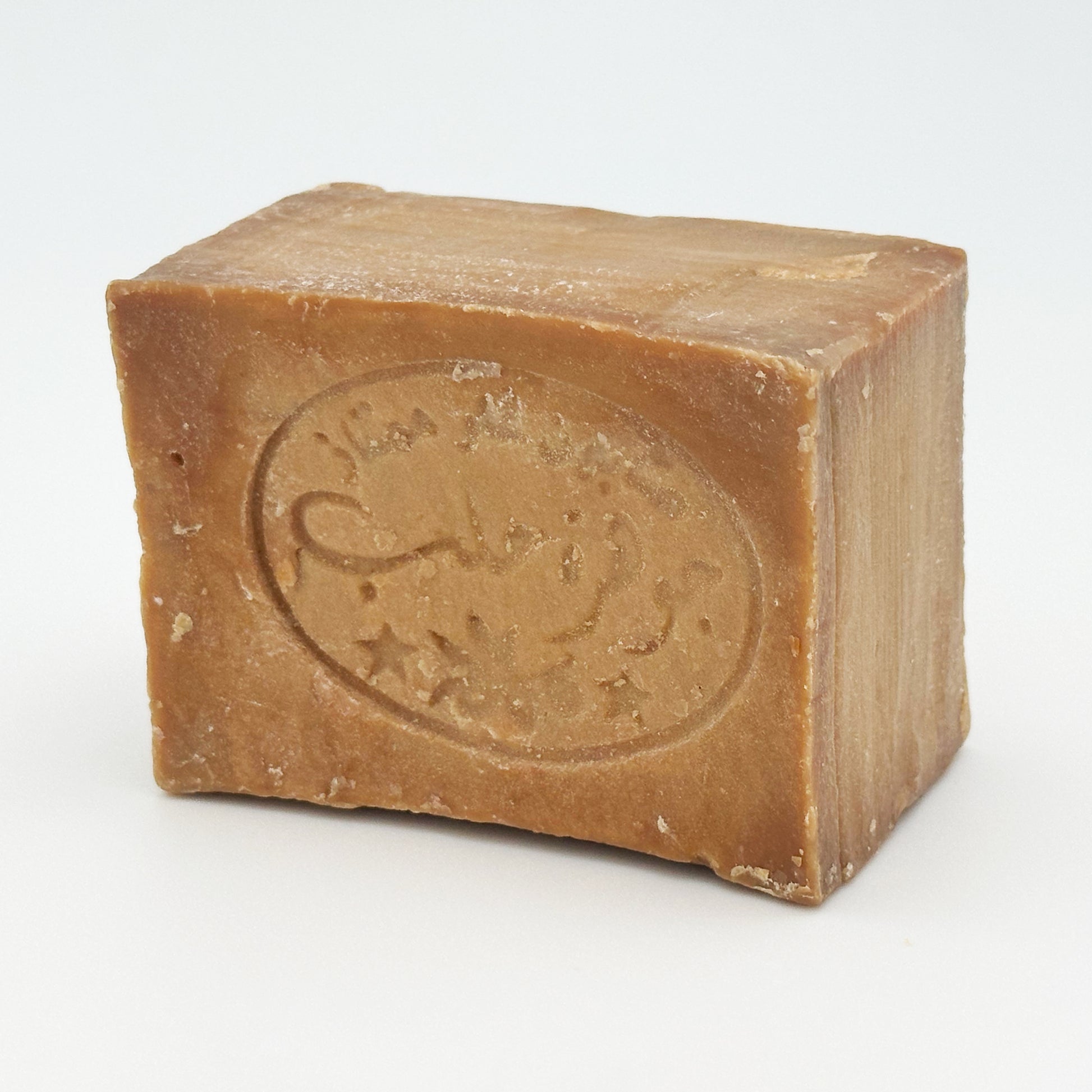 Avlia Aleppo soap bar angled slightly to show the top edge and traditional Arabic soap stamp