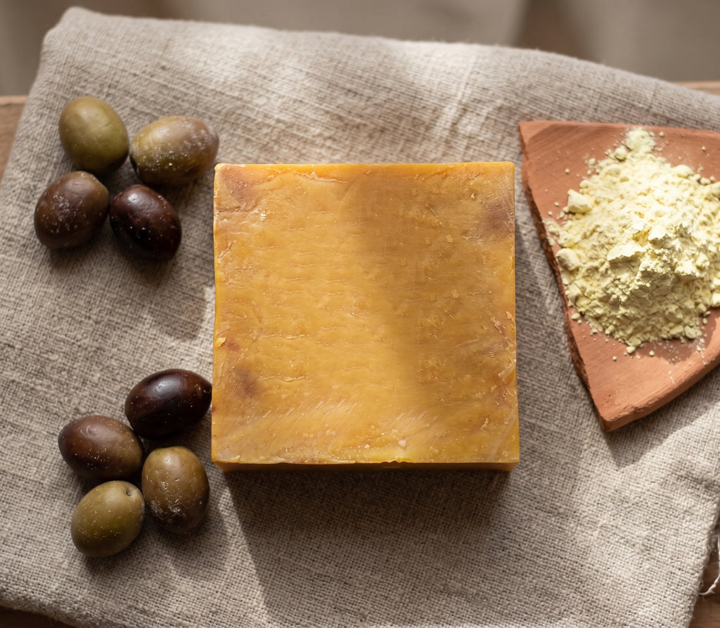 Avlia Pure Sulfur Soap with olives and mineral sulfur, ingredient story flatlay.