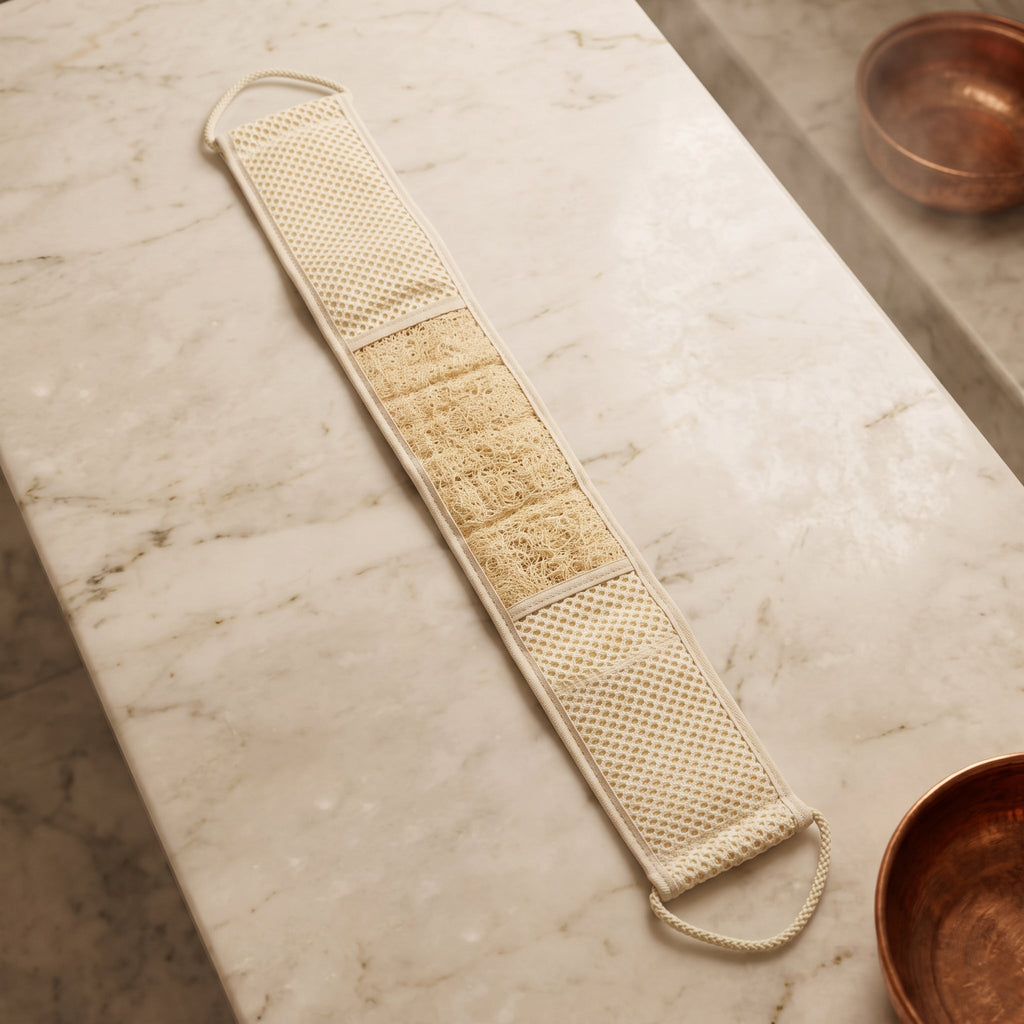 Avlia extra long loofah back strap laid beside a traditional Turkish kese mitt on pale marble, showing the two are different bath tools