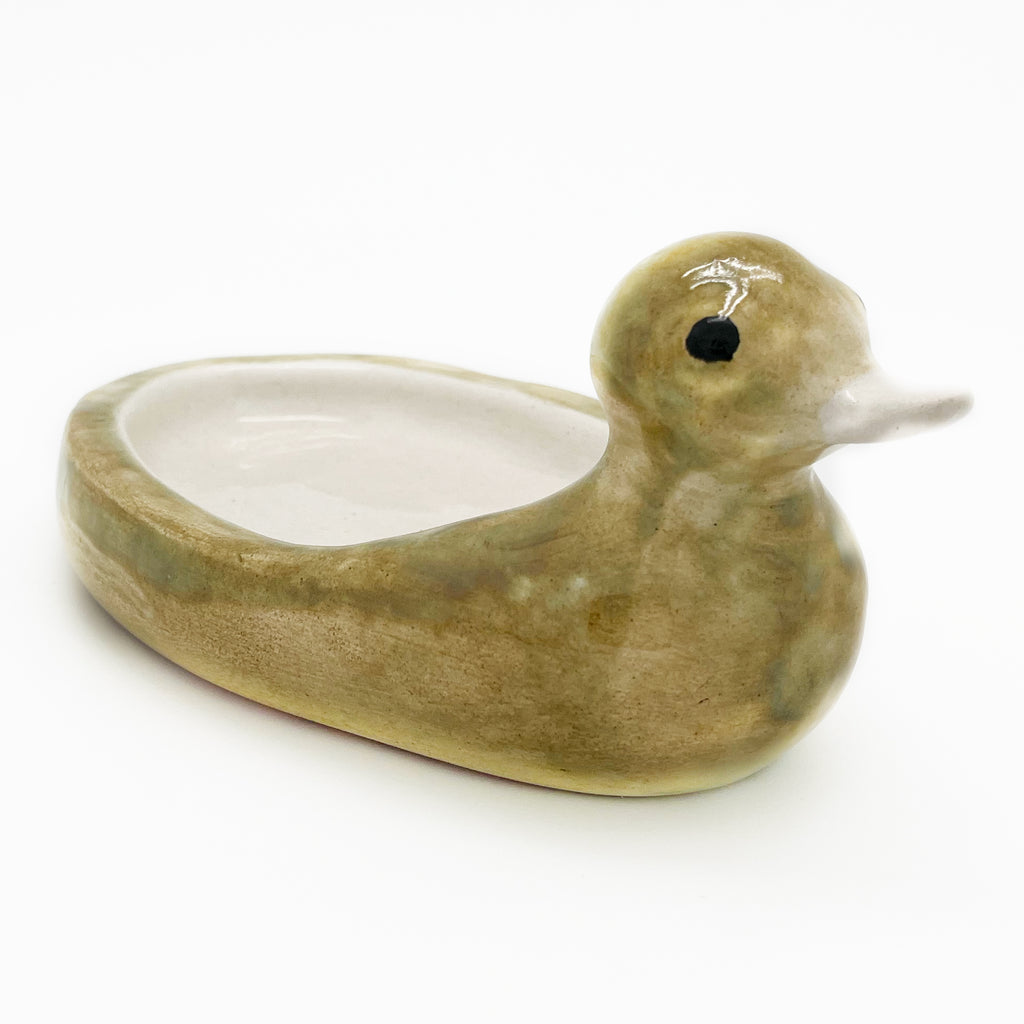 Avlia handmade ceramic duck soap dish in green-mustard glaze, three-quarter view with the empty cream bowl open towards the camera