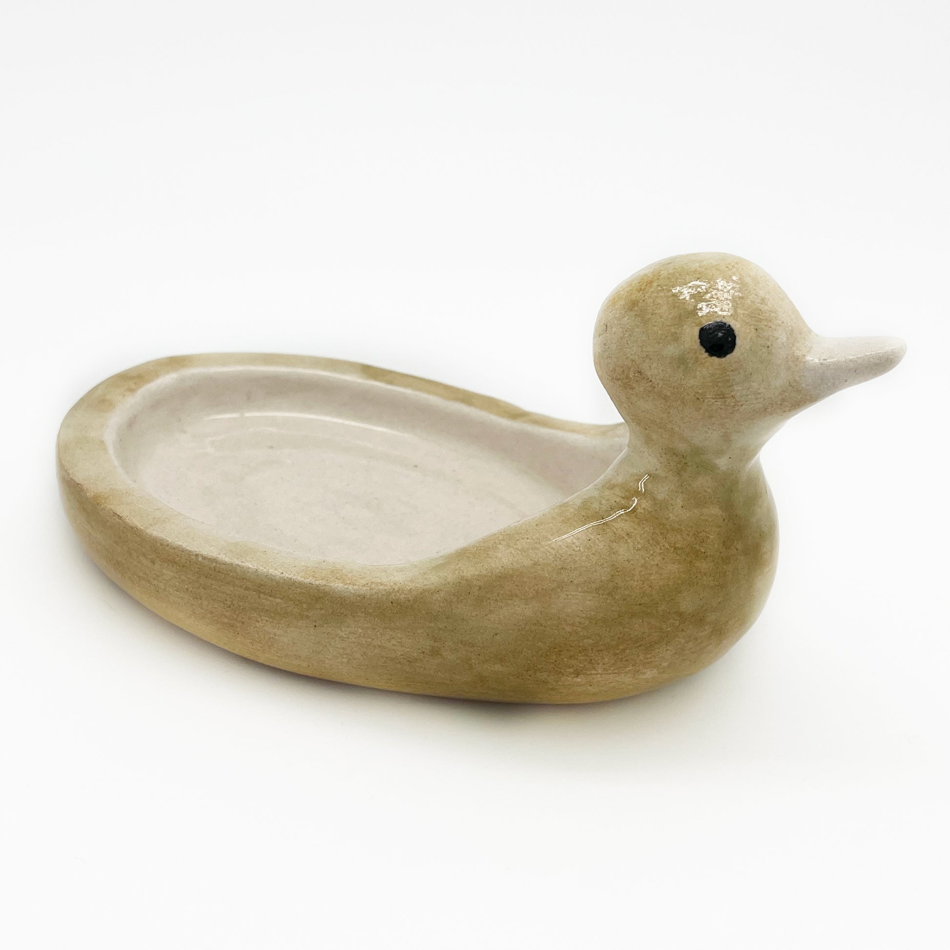 Avlia handmade ceramic duck soap dish in pale cream glaze seen from above, the shallow oval bowl formed by the hollowed back filling the frame