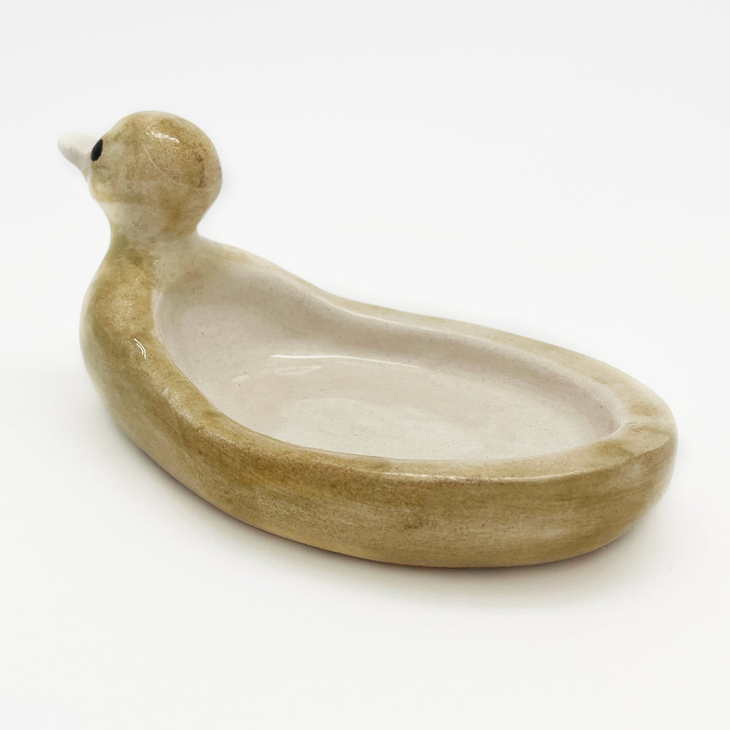 Avlia handmade ceramic duck soap dish in pale cream glaze, the head lifted and the long shallow bowl running back behind it towards the tail