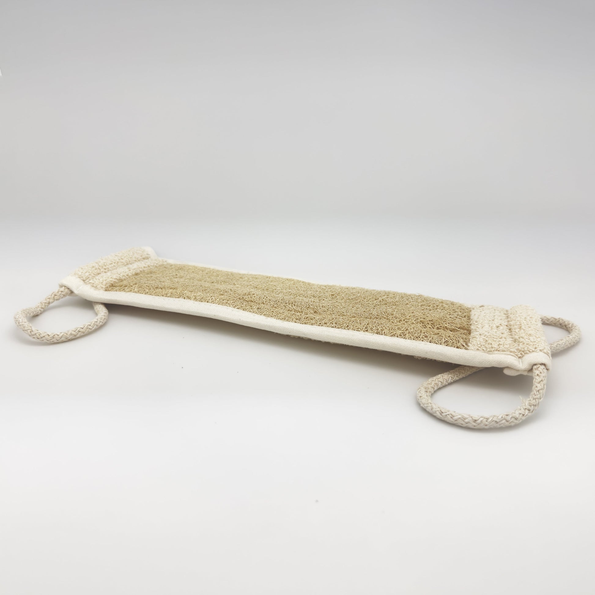 Avlia handmade loofah back strap in perspective, two cream braided cotton loops at the short ends for two-handed pulling across the back