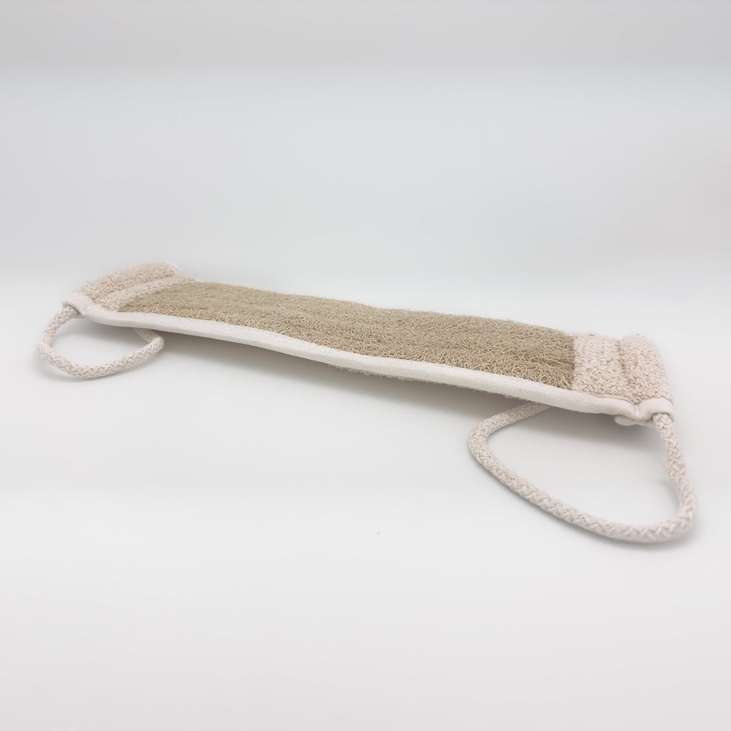 Avlia natural loofah back scrubber strap shown at an angle, tan loofah face with cream terry band at one end and two braided cotton handle loops