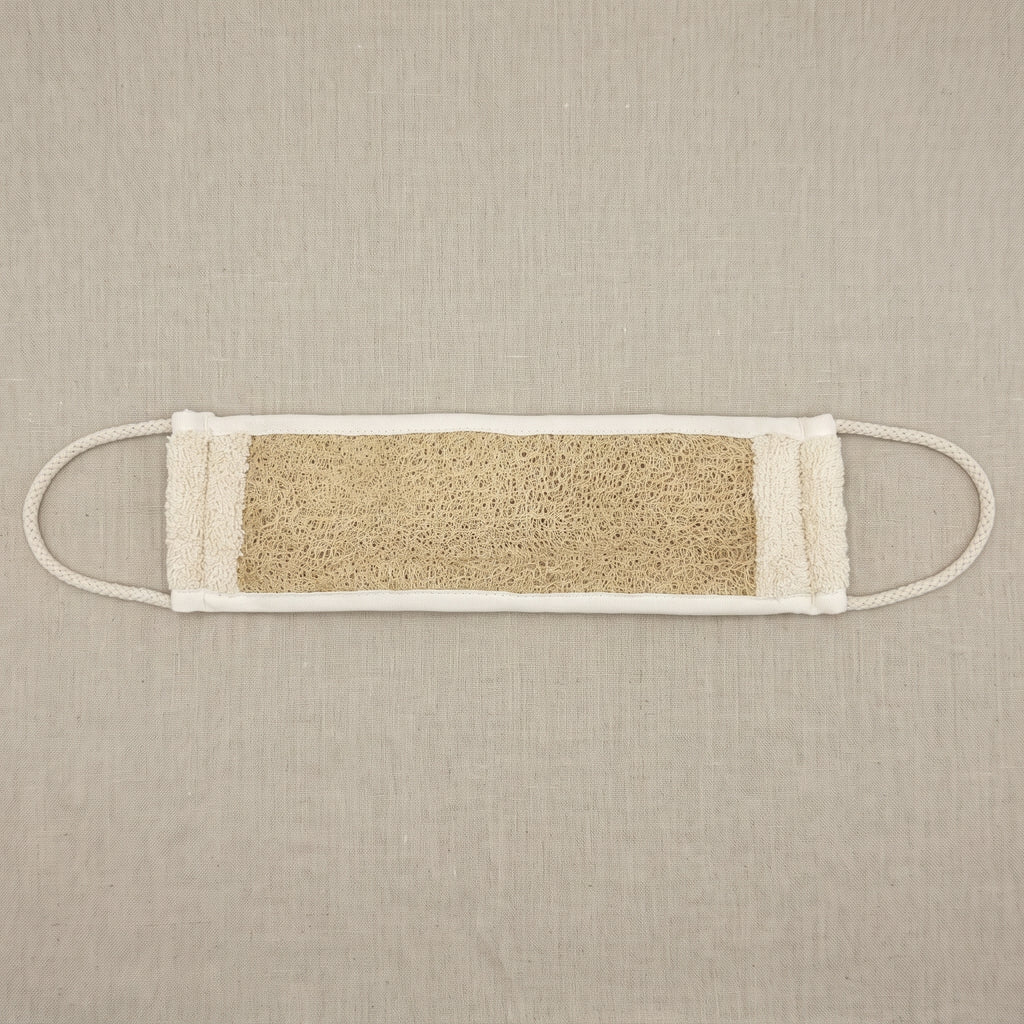 Avlia natural luffa back strap laid flat on linen, fully extended to its full length with a braided cotton loop stretched out at each short end