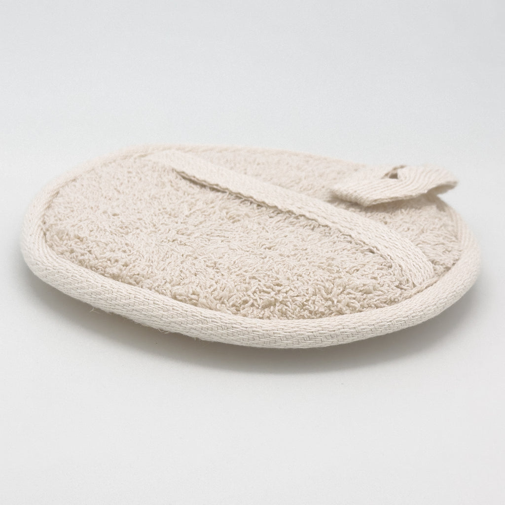 Back of round natural loofah pad with cream cotton terry cloth and single diagonal hand strap, eco body scrubber