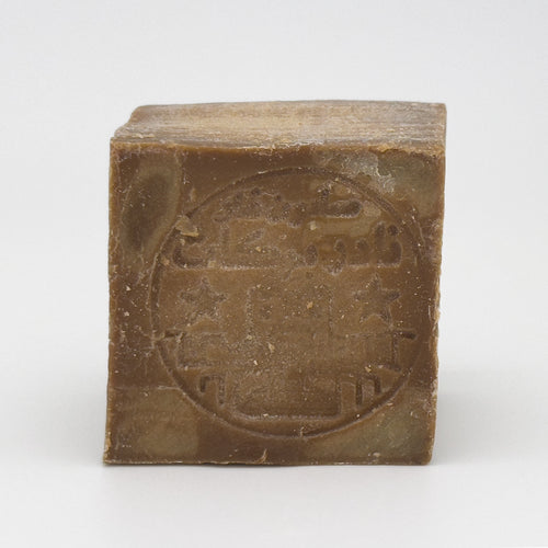 Close-up front view of Aleppo soap bar with circular impressed logo and Arabic calligraphy