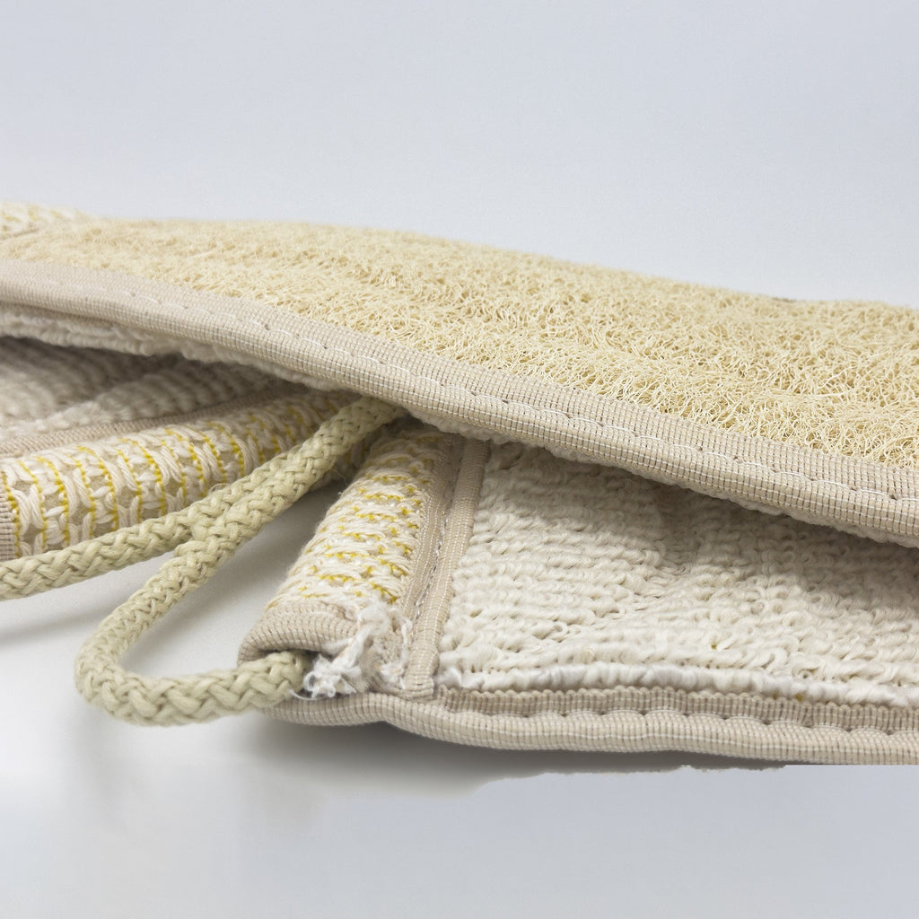 Close-up of the Avlia back strap edge showing the loofah panel, the waffle-knit cotton zone beside it and the cream terry reverse face underneath