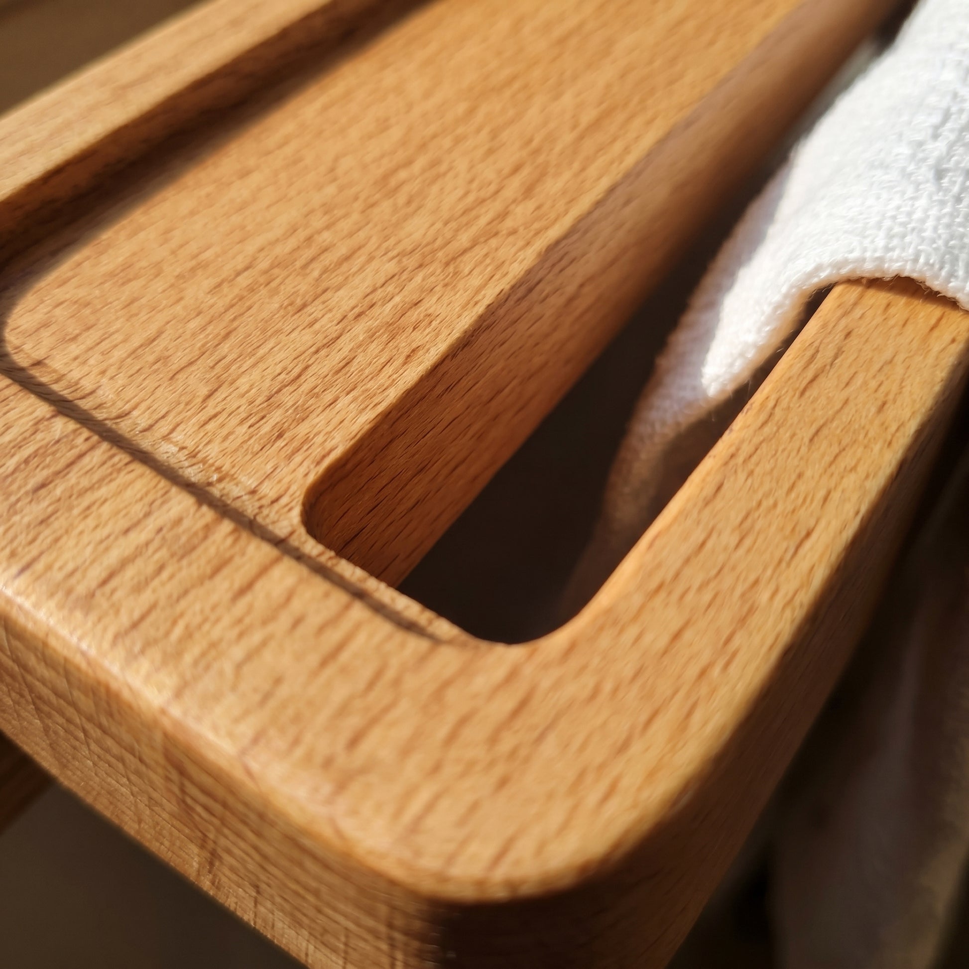 Close-up detail of Avlia beechwood towel shelf CNC-machined slot edge on top face, natural wood grain transition, precision bathroom accessory