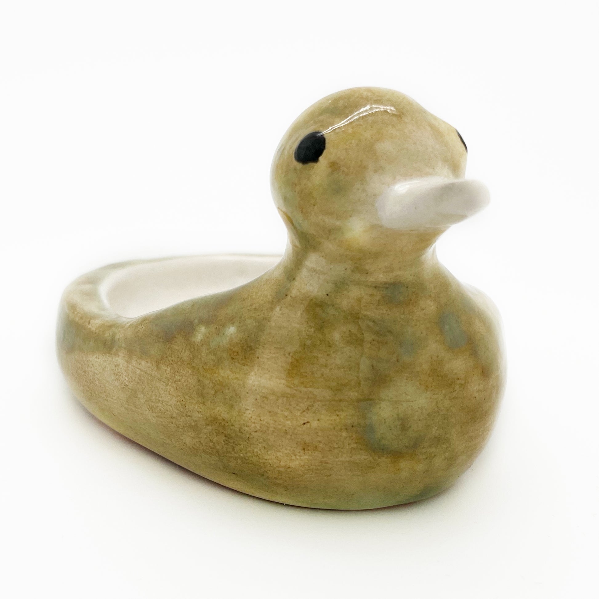 Close three-quarter view of the Avlia ceramic duck soap dish, the hand-modelled head and cream beak in focus with the shallow bowl behind