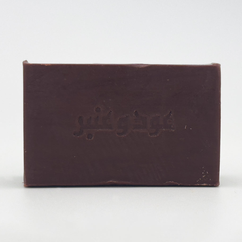 Direct front view of Avlia Oud & Anbar soap bar with clear, centered Arabic text engraving on a white background