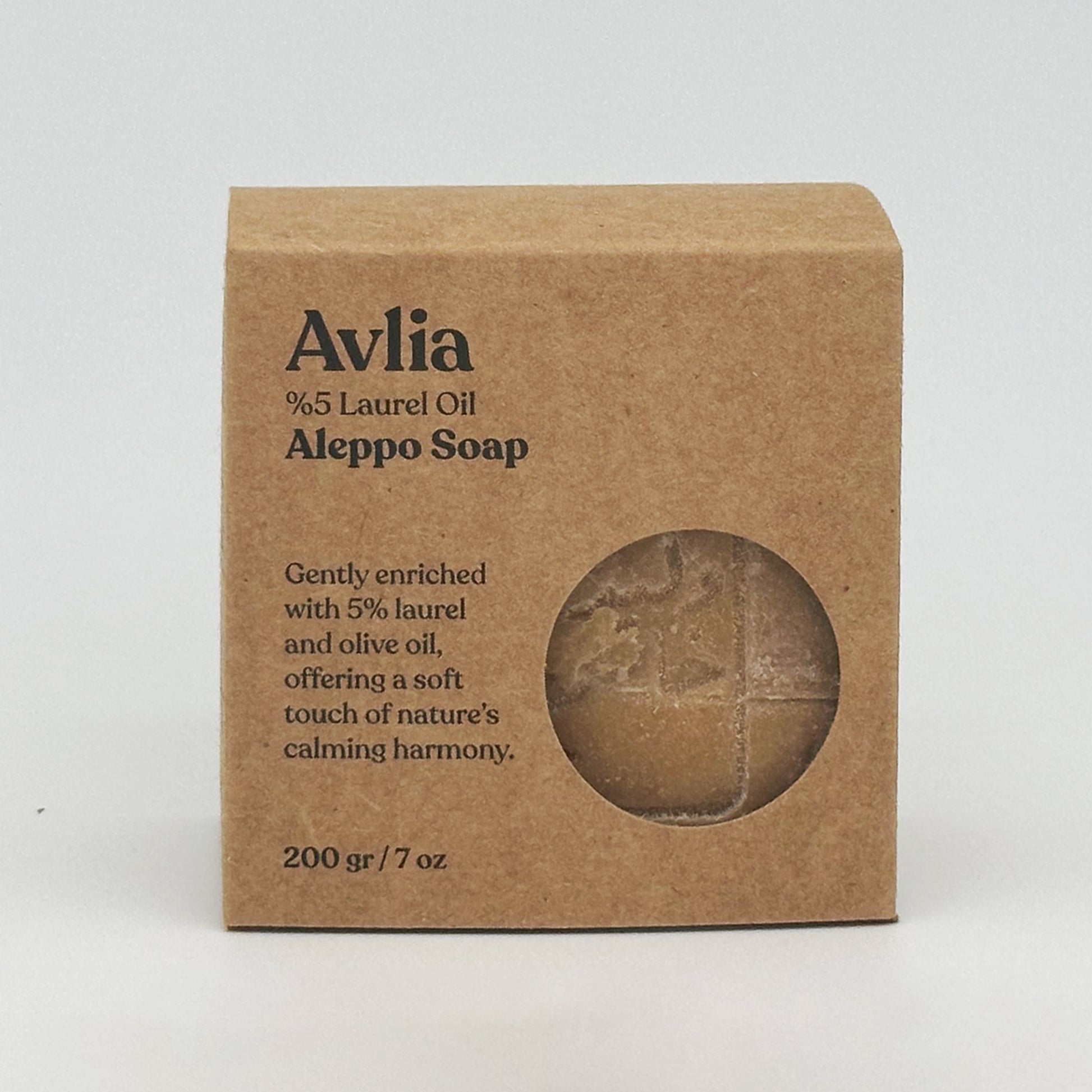 Front view of the Avlia Aleppo Soap box. The kraft paper packaging features the brand name "Avlia" in a serif font, "5% Laurel Oil Aleppo Soap," and a circular cutout revealing the textured, stamped soap bar inside