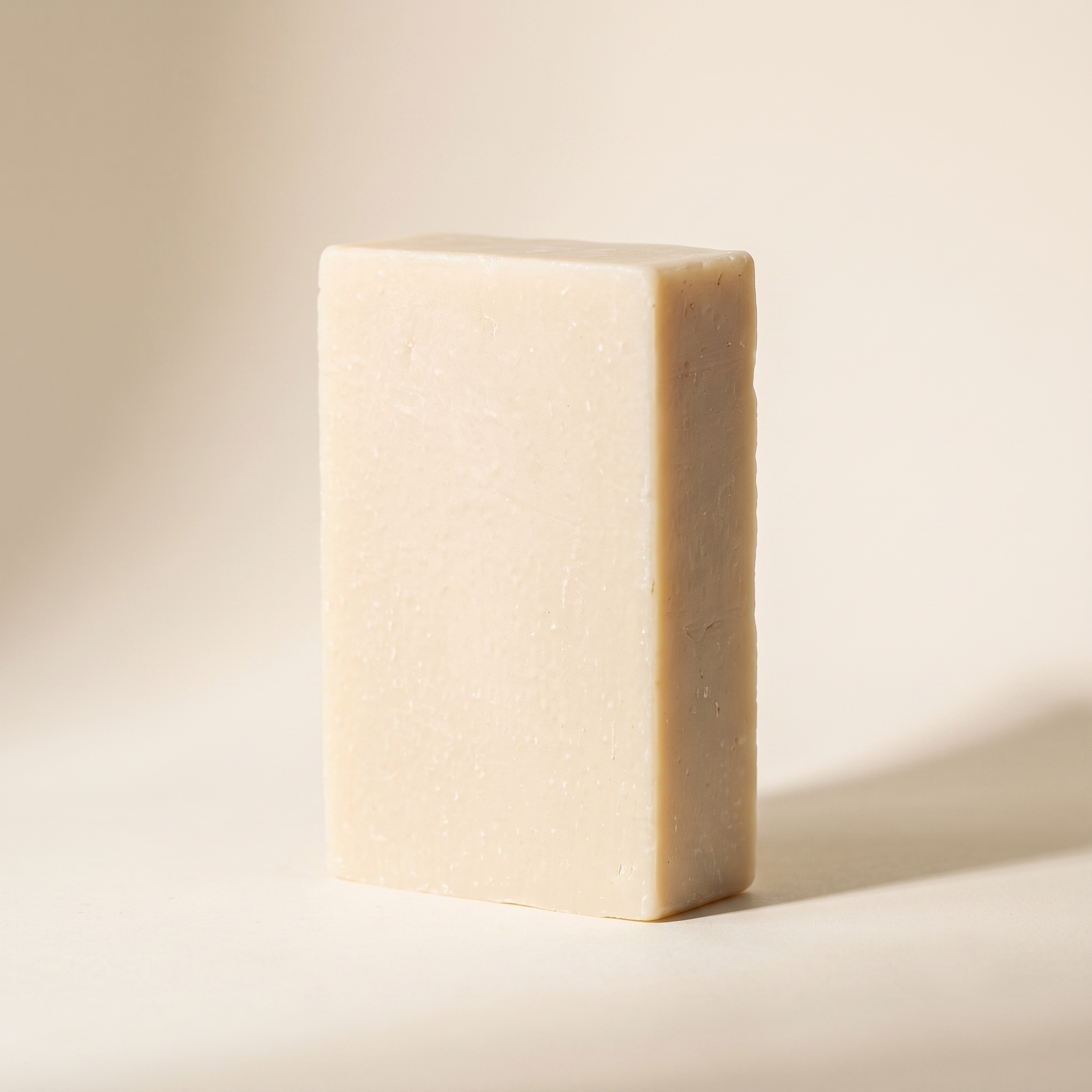 Goat Milk Soap standing on edge against a warm off-white backdrop, showing its hand-cut thickness