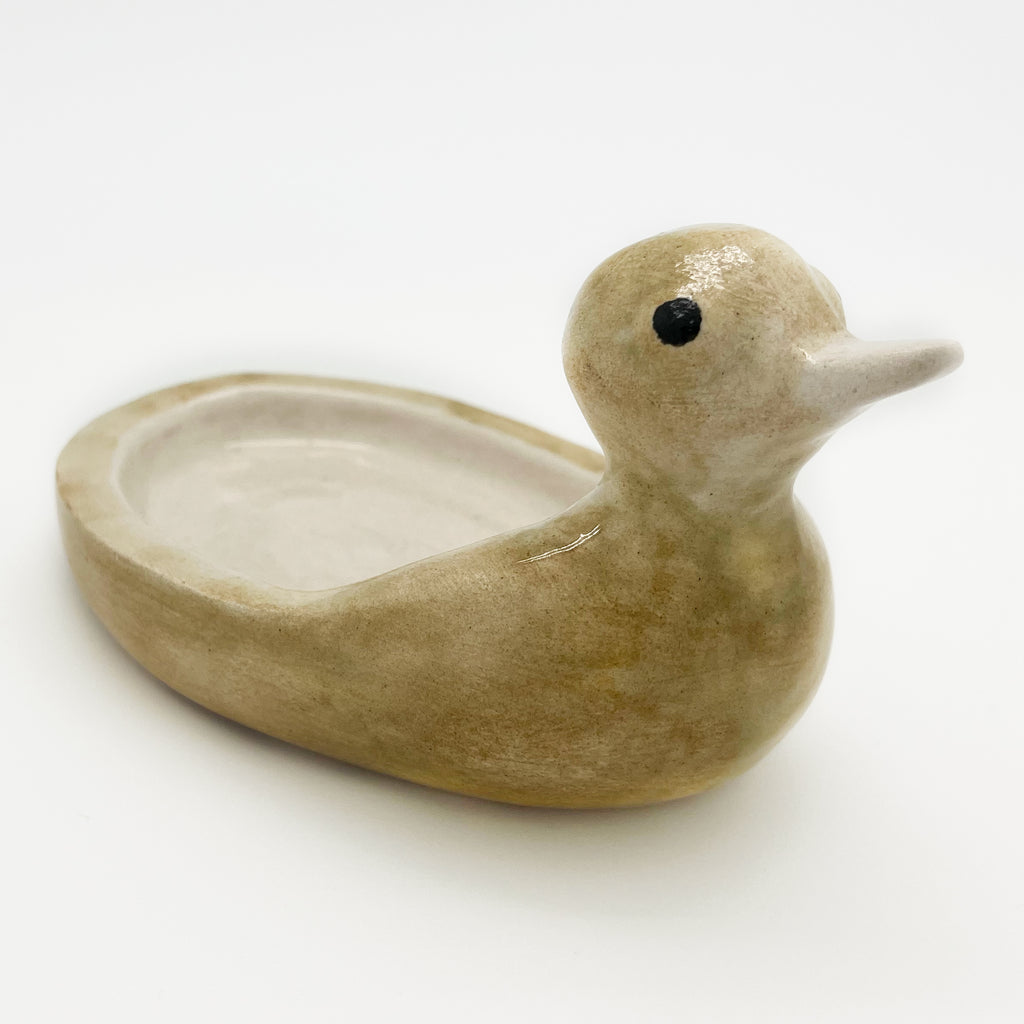The pale cream glaze of the Avlia ceramic duck soap dish, matt and softly speckled where it thins over the curve of the breast