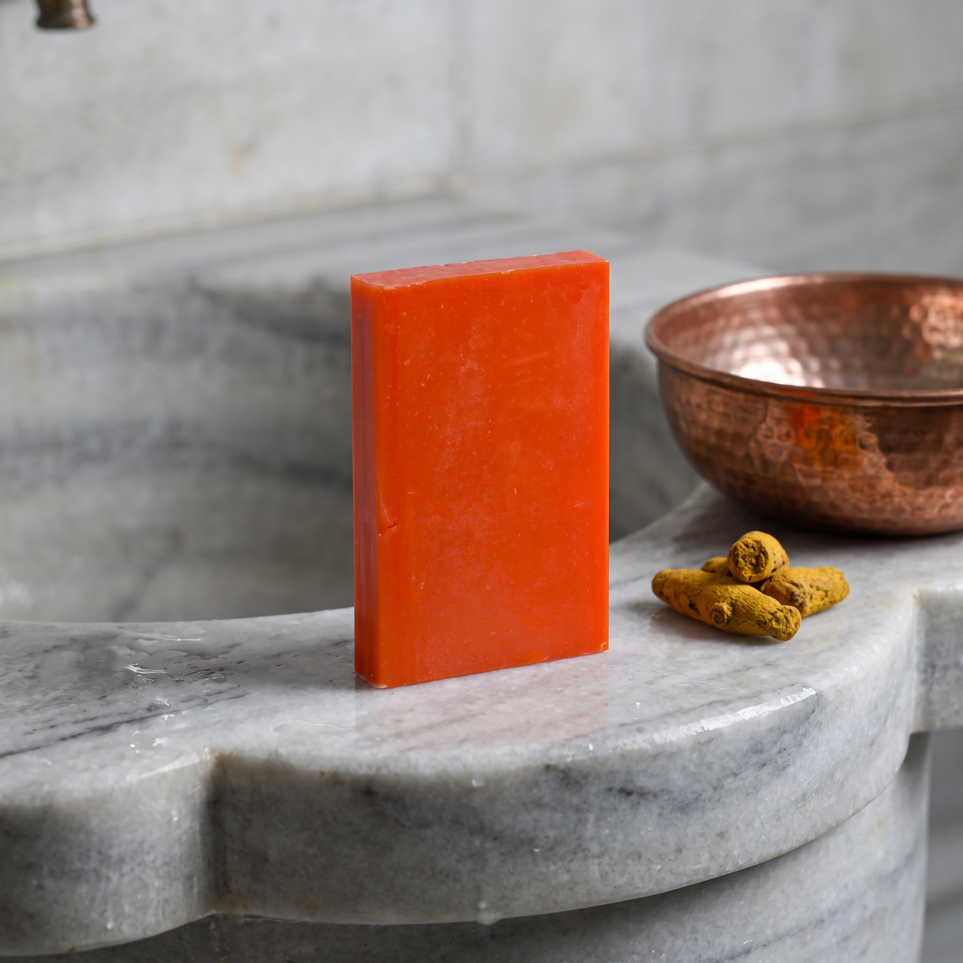 Avlia Kojic Acid & Turmeric Soap Bar on marble hammam basin edge with copper bowl