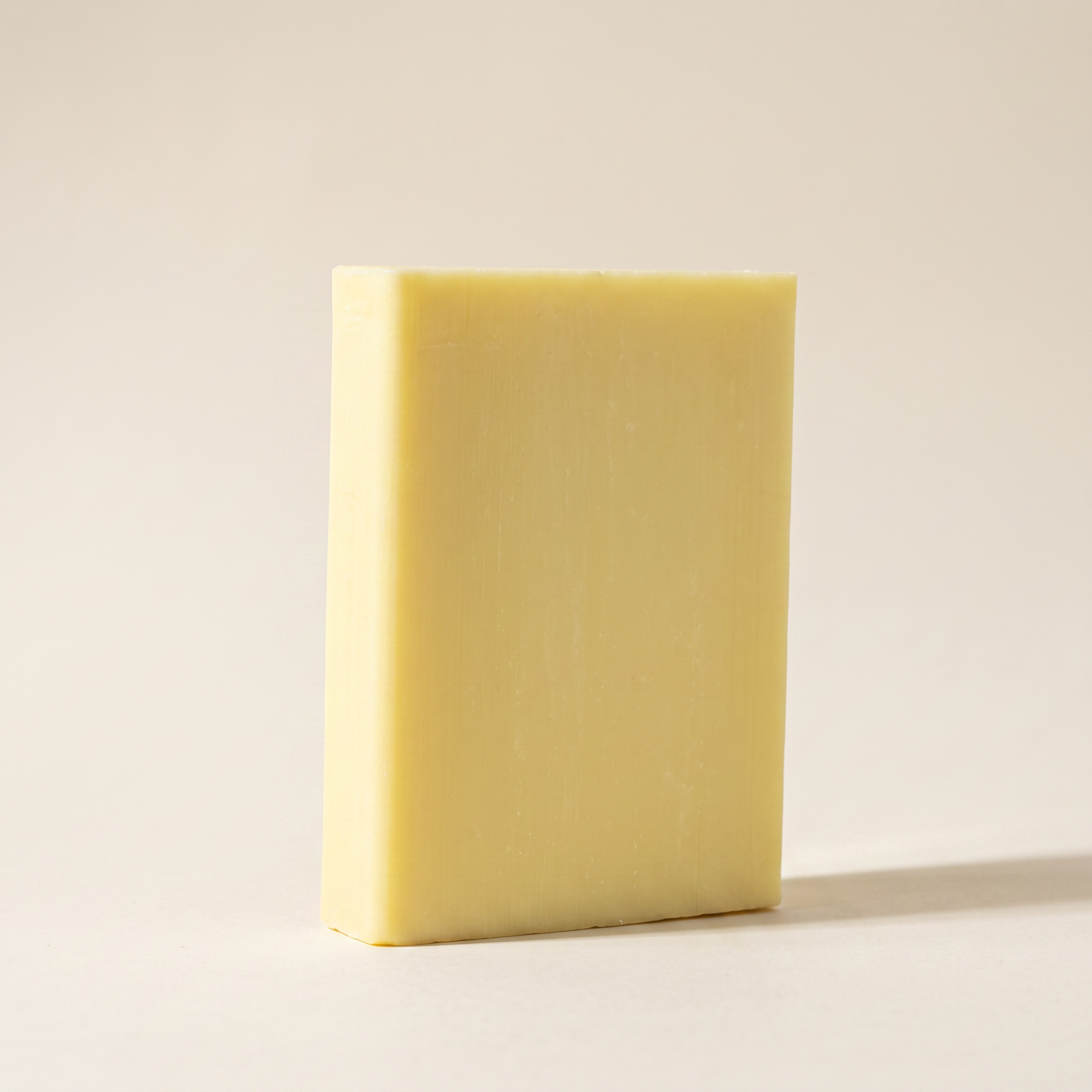 Lemon Soap Bar standing on edge against a warm off-white backdrop, showing its hand-cut thickness