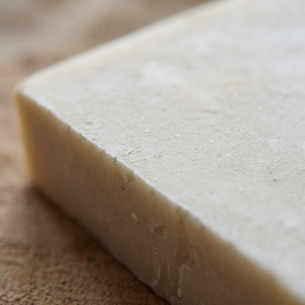 Macro close-up of the donkey milk soap's rough hand-cut edge and pale, milk-white texture.