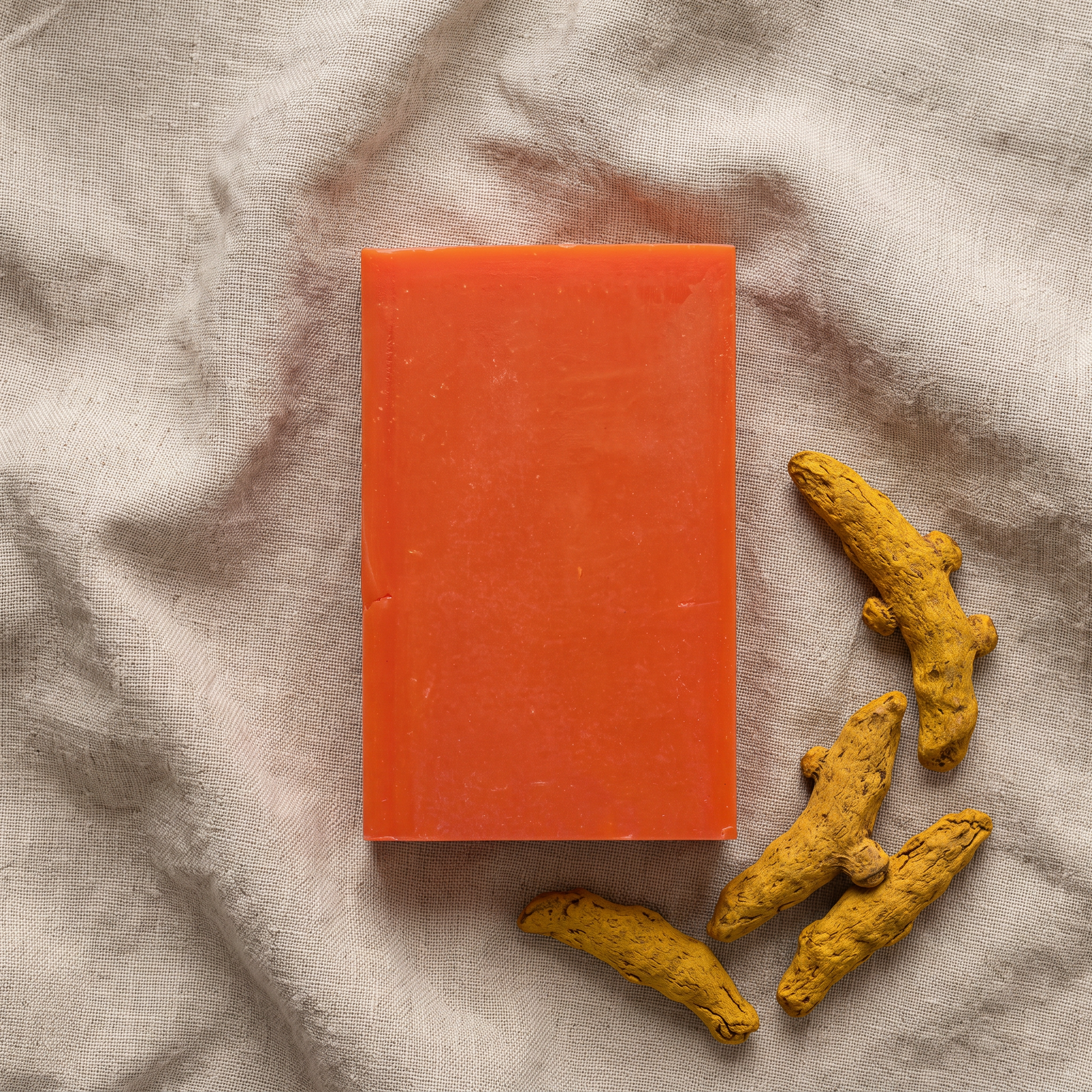 Avlia Kojic Acid & Turmeric Soap Bar flat-lay on natural linen with dried turmeric root