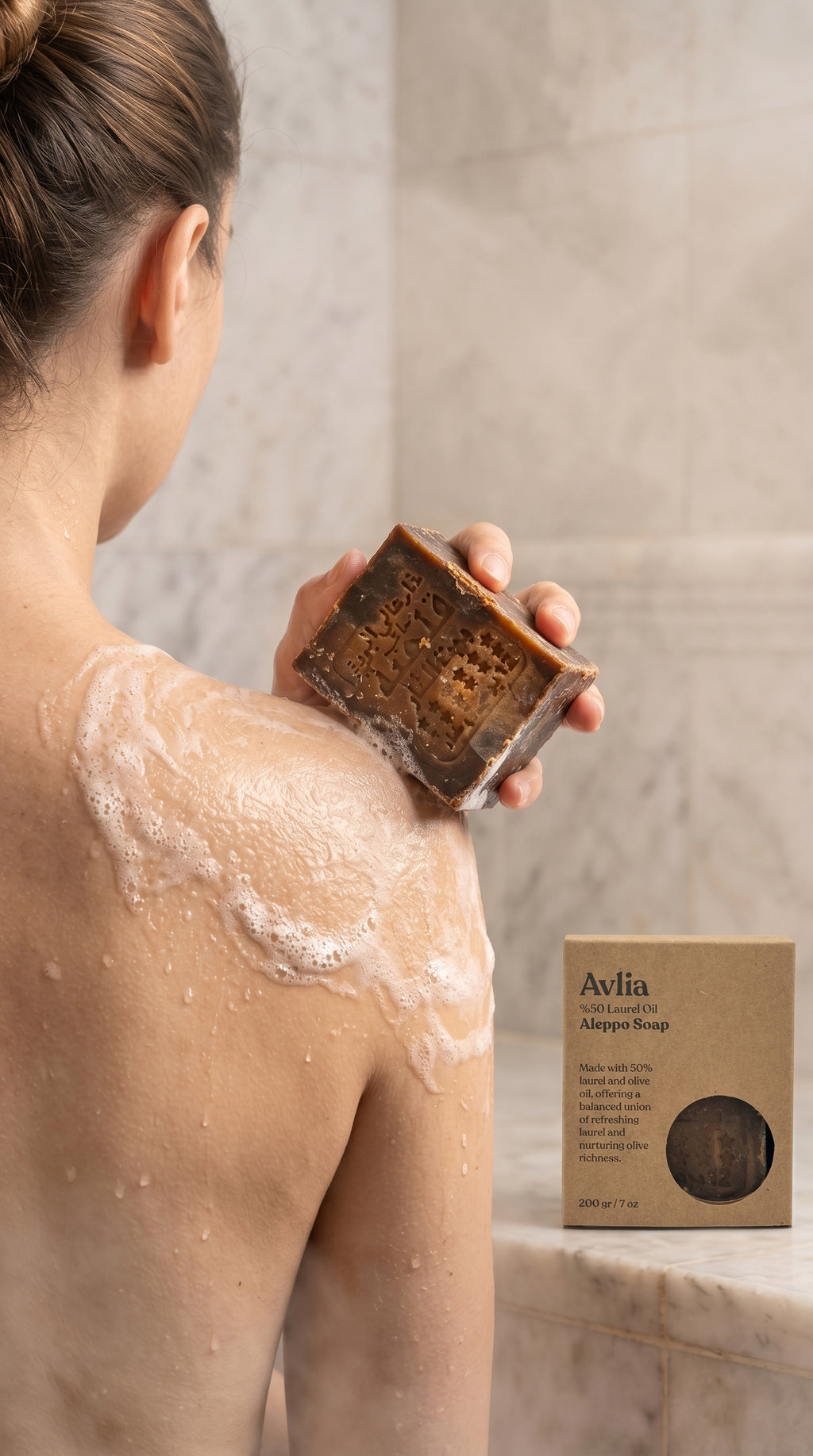 Person using Avlia 50% Laurel Oil Aleppo Soap bar on shoulders in hammam spa setting, traditional Turkish bath ritual with natural handmade olive oil and laurel soap