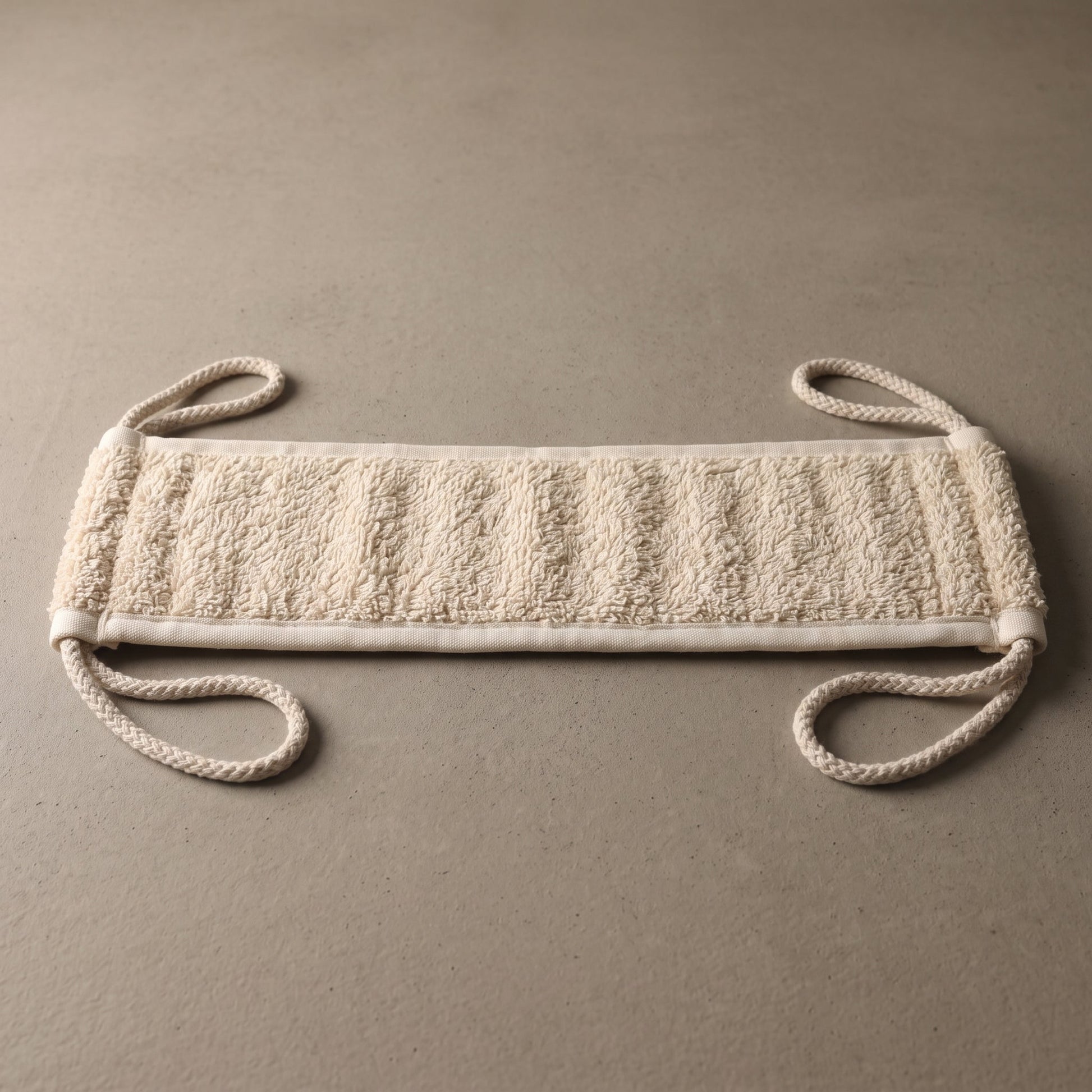 Reverse side of the Avlia back strap showing the full-length cream cotton terry face, the softer surface, framed by woven cotton binding along every edge