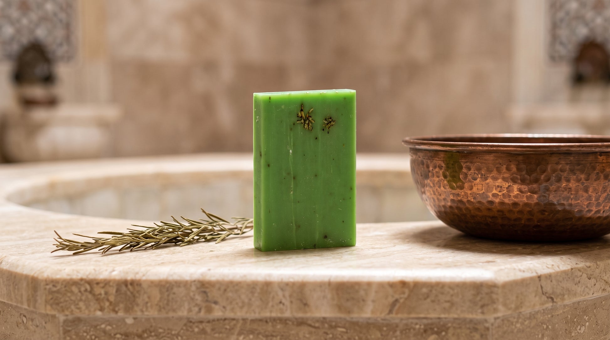 Rosemary Soap Bar on the marble edge of a Turkish hammam basin with a hammered copper bowl