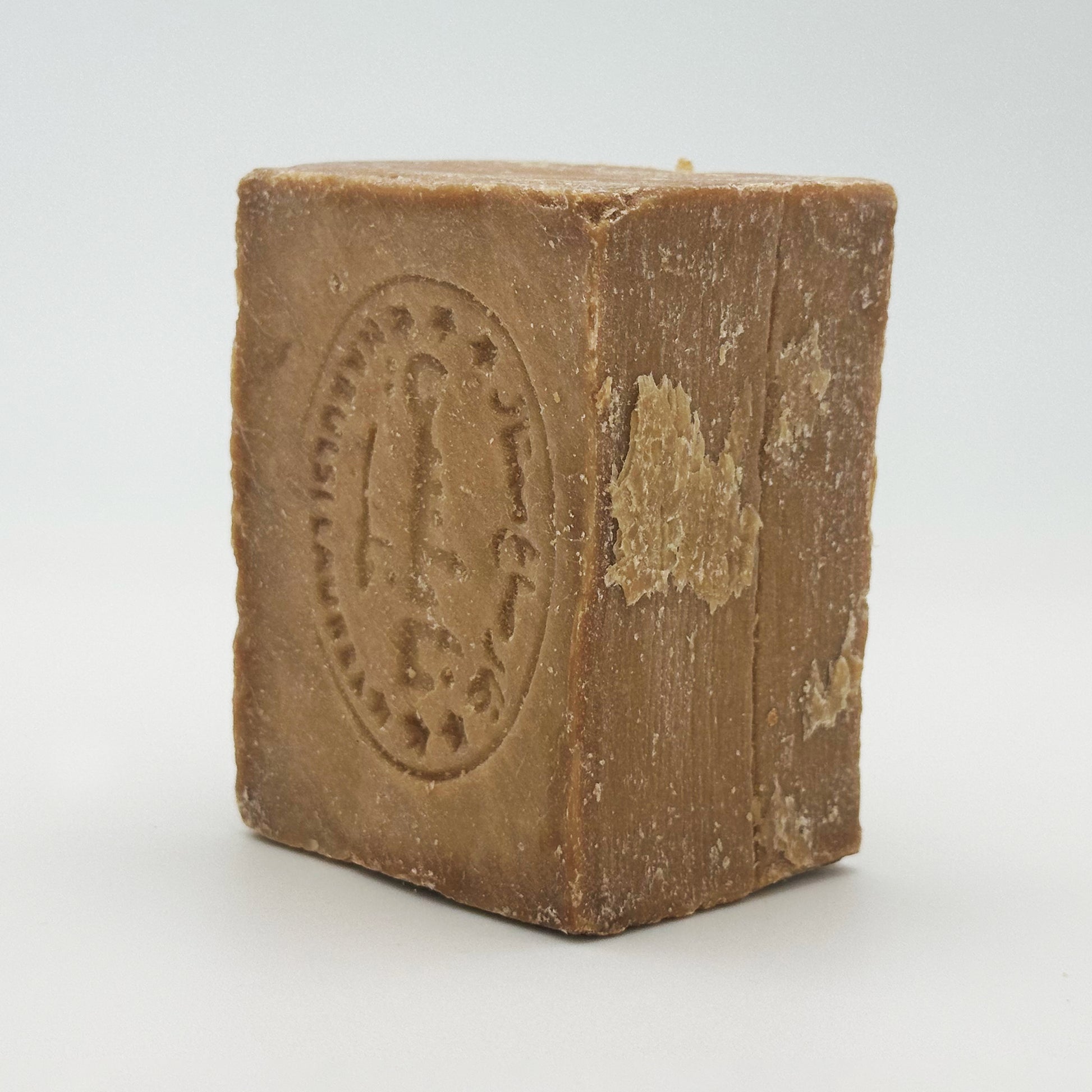Side angle view of a standing Avlia Nablus soap bar showing rustic texture and stamped logo
