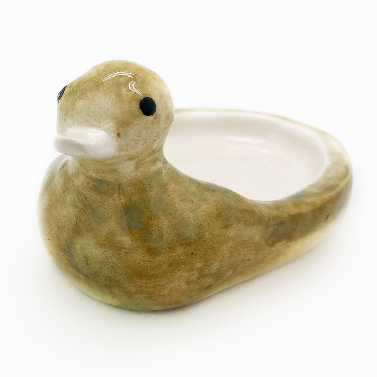 The cream-glazed interior of the Avlia ceramic duck soap dish, its uneven hand-applied glaze pooling darker where the surface dips towards the rim