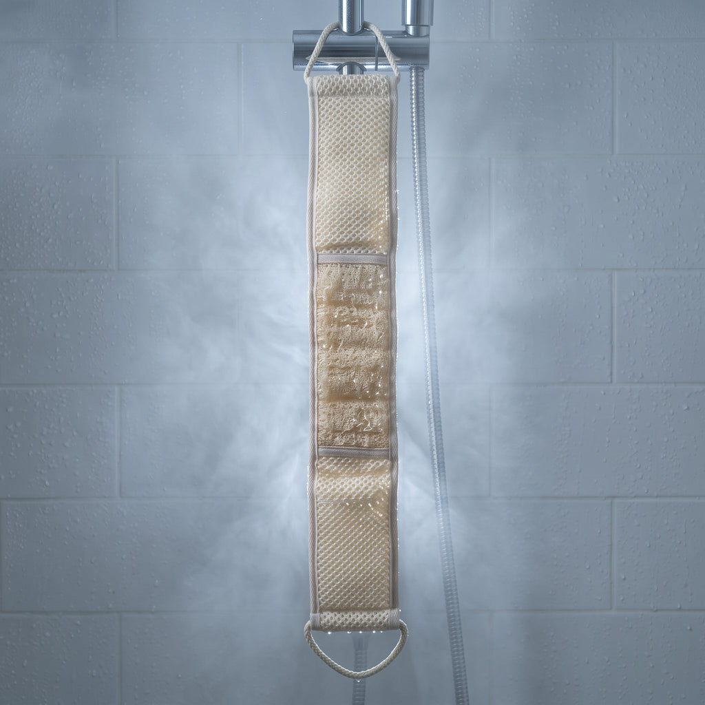Wet Avlia loofah back strap hanging full length from a shower rail, water droplets on the loofah panel and the waffle-knit cotton
